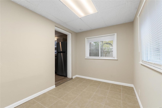 empty room featuring a drop ceiling and light tile patterned flooring