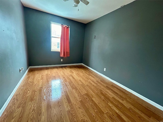 empty room featuring ceiling fan, baseboards, and wood finished floors