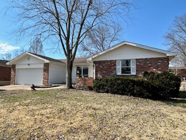 ranch-style house with a front yard, concrete driveway, brick siding, and an attached garage