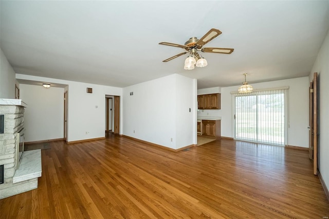 unfurnished living room with baseboards, a ceiling fan, wood finished floors, and a fireplace