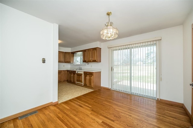 kitchen featuring visible vents, dishwasher, light countertops, light wood-type flooring, and a sink