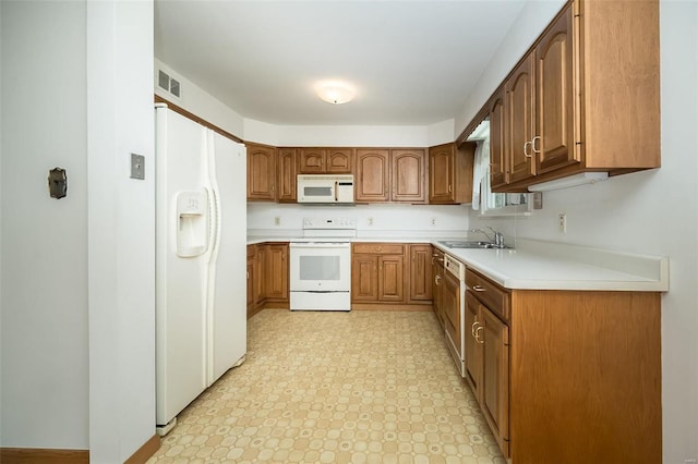 kitchen featuring white appliances, brown cabinets, visible vents, and a sink