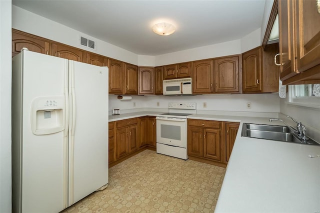 kitchen with visible vents, light countertops, brown cabinets, white appliances, and a sink