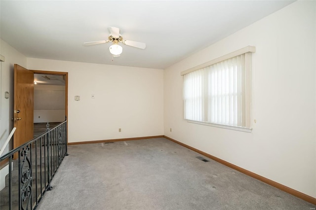 carpeted empty room with visible vents, baseboards, and ceiling fan