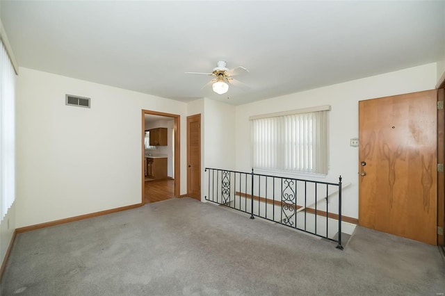 unfurnished room featuring visible vents, baseboards, carpet, and a ceiling fan