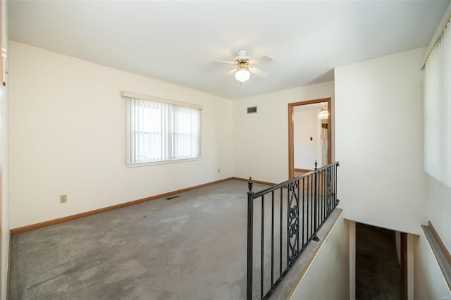 empty room with carpet, baseboards, visible vents, and a ceiling fan