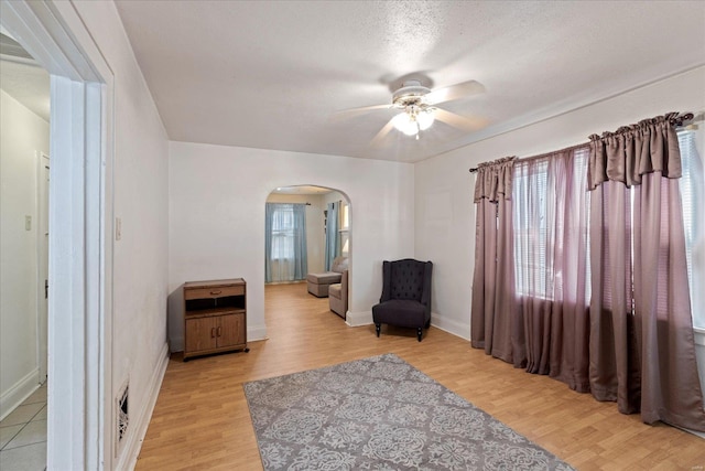 living area featuring ceiling fan, light hardwood / wood-style floors, and a textured ceiling