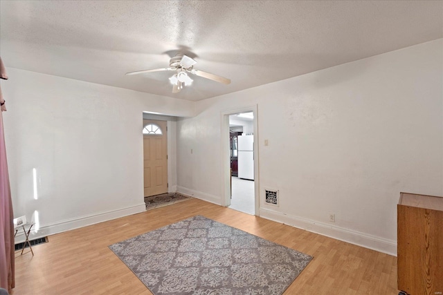 foyer entrance with hardwood / wood-style flooring, ceiling fan, and a textured ceiling