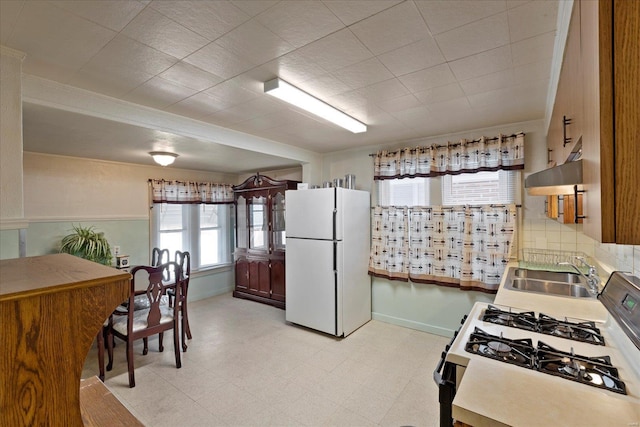 kitchen featuring sink, crown molding, backsplash, white refrigerator, and gas range oven