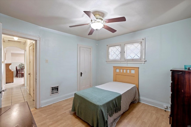 bedroom featuring heating unit, light hardwood / wood-style floors, and ceiling fan