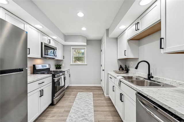 kitchen featuring appliances with stainless steel finishes, sink, light wood-type flooring, and white cabinets