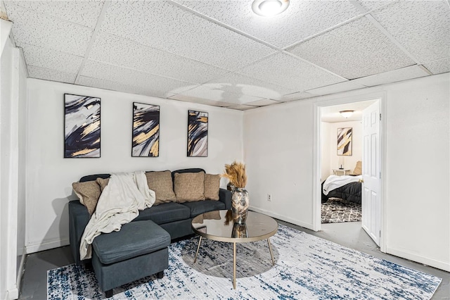 living room featuring a drop ceiling and concrete flooring