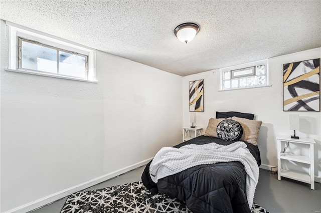 bedroom featuring a textured ceiling, multiple windows, and concrete flooring