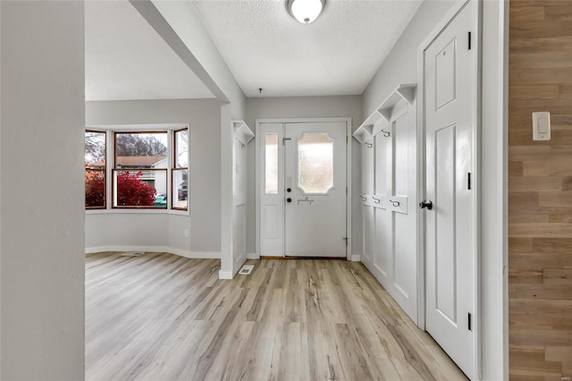 foyer entrance featuring light hardwood / wood-style floors and a textured ceiling