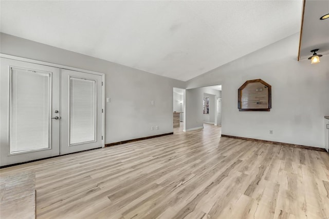 unfurnished living room with french doors, light wood-type flooring, ceiling fan, and lofted ceiling