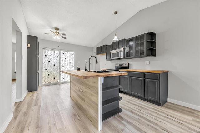 kitchen with appliances with stainless steel finishes, light wood-type flooring, sink, pendant lighting, and butcher block counters