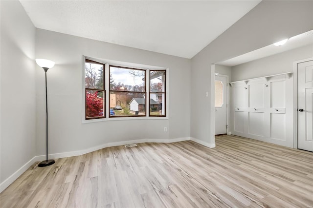 unfurnished bedroom featuring a textured ceiling, light hardwood / wood-style floors, and vaulted ceiling