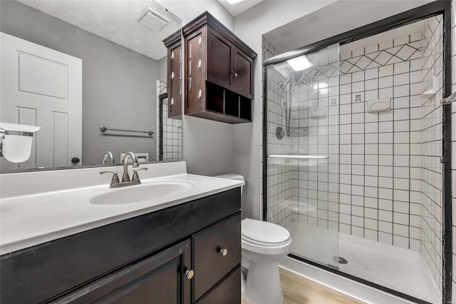 bathroom with hardwood / wood-style flooring, vanity, toilet, and an enclosed shower