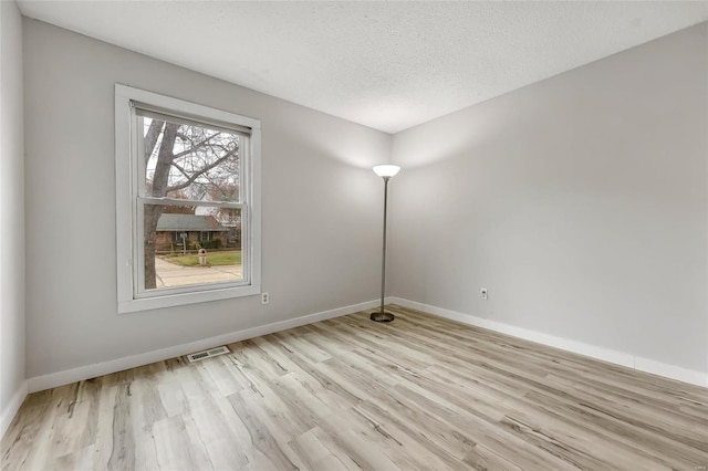 unfurnished room with light wood-type flooring and a textured ceiling