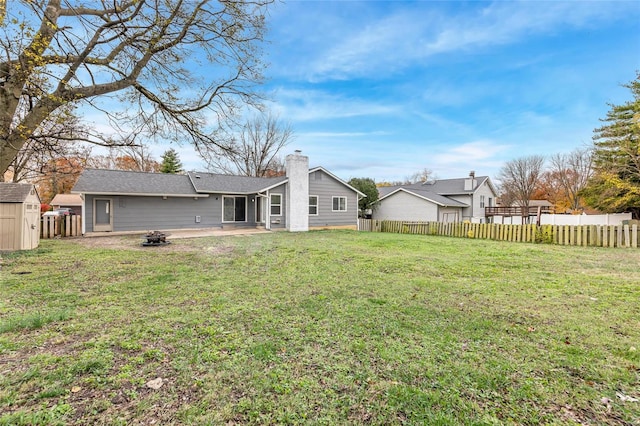 rear view of property featuring a fire pit, a patio area, and a lawn