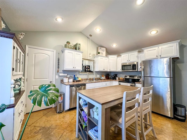 kitchen featuring sink, appliances with stainless steel finishes, lofted ceiling, and white cabinets