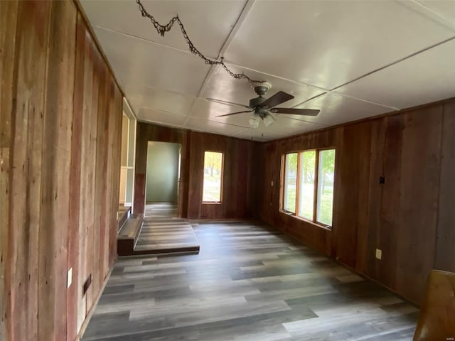 unfurnished room featuring hardwood / wood-style floors, wooden walls, and ceiling fan