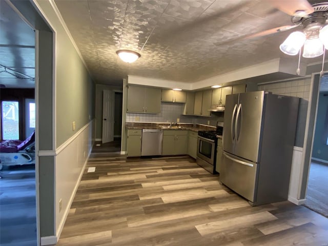 kitchen with ceiling fan, crown molding, appliances with stainless steel finishes, and wood-type flooring