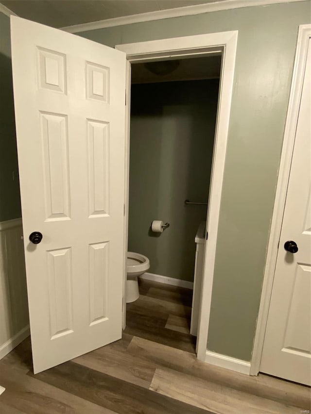 bathroom with crown molding, wood-type flooring, and toilet