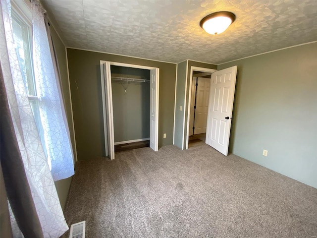 unfurnished bedroom featuring carpet, a textured ceiling, and a closet