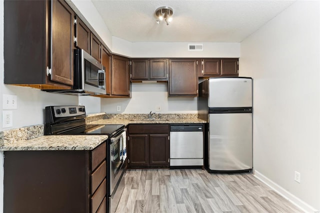 kitchen with dark brown cabinets, appliances with stainless steel finishes, a textured ceiling, light hardwood / wood-style flooring, and sink