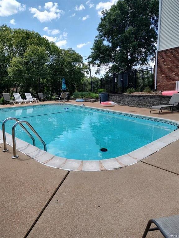 view of swimming pool featuring a patio area and a diving board