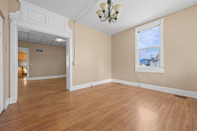 spare room with a chandelier, a drop ceiling, and wood-type flooring