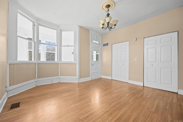 unfurnished bedroom featuring an inviting chandelier and wood-type flooring