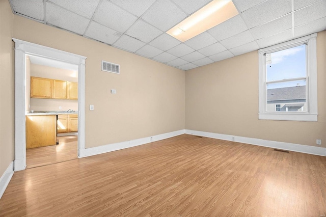 spare room featuring a drop ceiling and light wood-type flooring