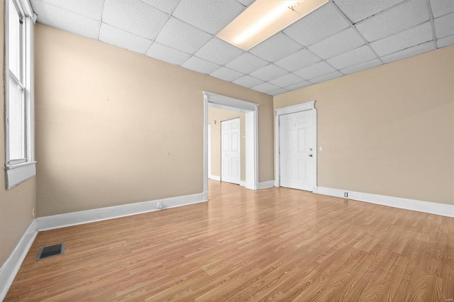 unfurnished room featuring light hardwood / wood-style floors and a paneled ceiling