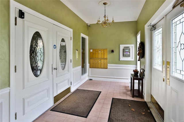 tiled foyer entrance with a chandelier, a healthy amount of sunlight, and ornamental molding