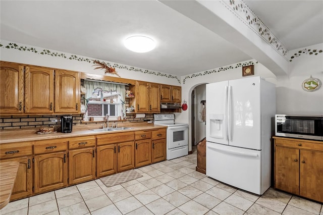 kitchen with light tile patterned floors, sink, white appliances, and tasteful backsplash