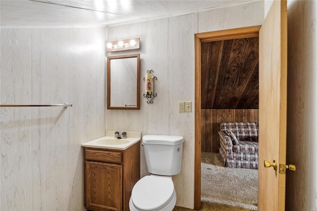 bathroom with vanity, wood walls, and toilet