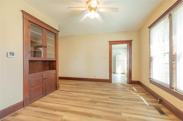 unfurnished room with ceiling fan, a healthy amount of sunlight, and light wood-type flooring