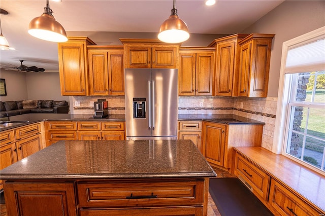 kitchen with backsplash, pendant lighting, a kitchen island, and stainless steel fridge