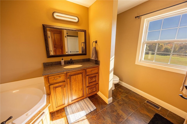 bathroom with vanity, toilet, and a tub to relax in