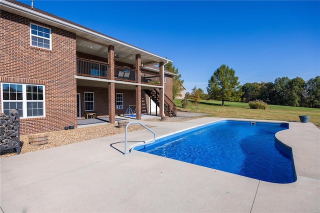 view of pool with a patio area and a lawn