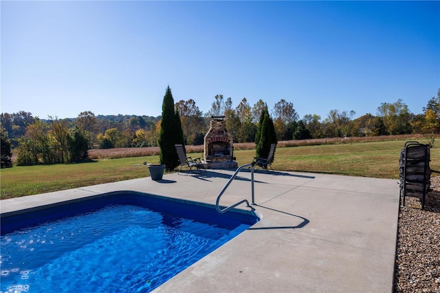 view of pool featuring a yard, a patio area, and an outdoor stone fireplace