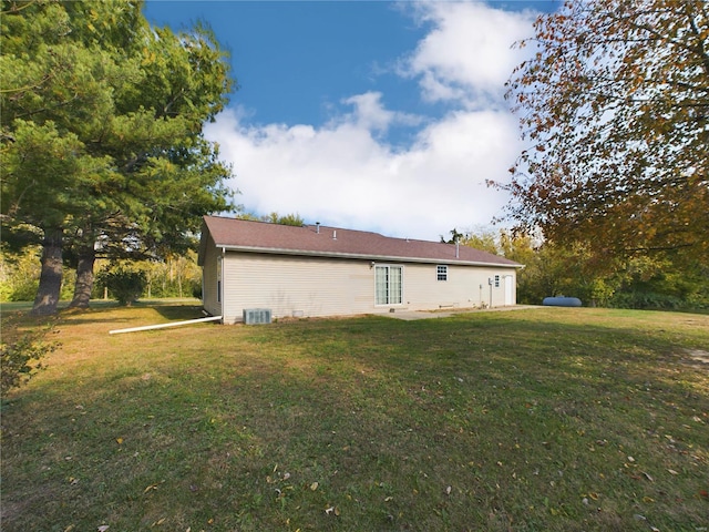 back of house featuring central air condition unit and a lawn