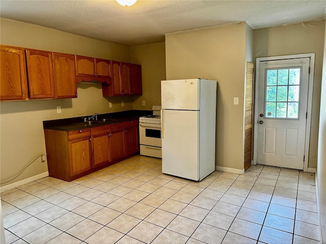 kitchen with a textured ceiling, sink, light tile patterned floors, and white appliances