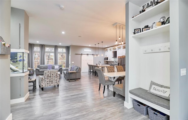 living room with a barn door and light wood-type flooring