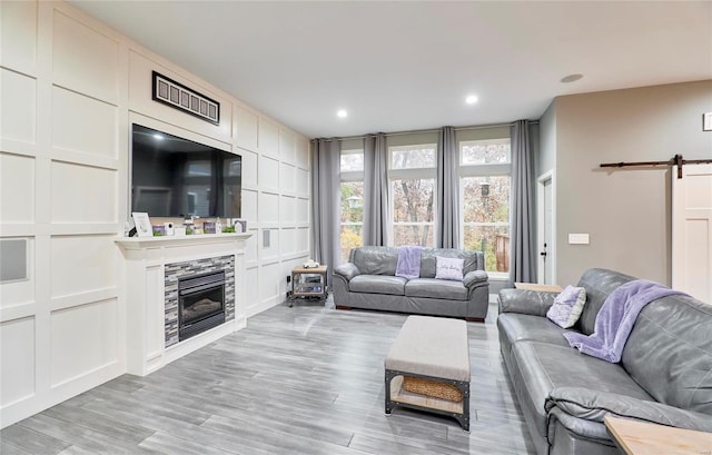 living room featuring a fireplace, a barn door, and light hardwood / wood-style flooring