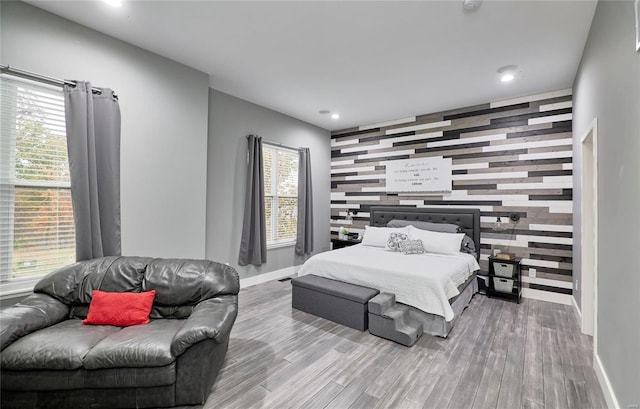 bedroom with hardwood / wood-style floors, multiple windows, and tile walls