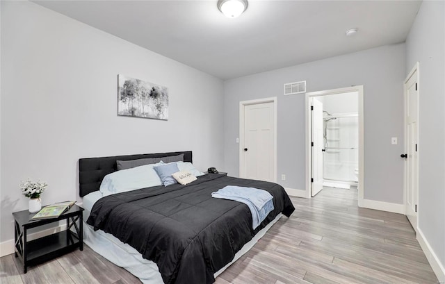 bedroom featuring connected bathroom and light hardwood / wood-style flooring