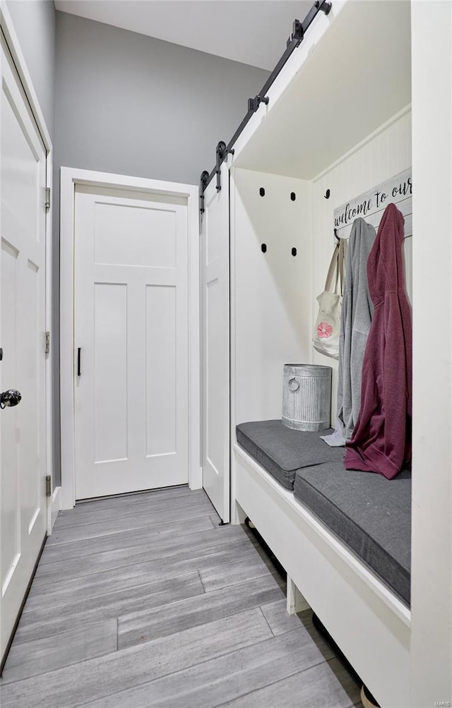 mudroom with a barn door and light hardwood / wood-style floors